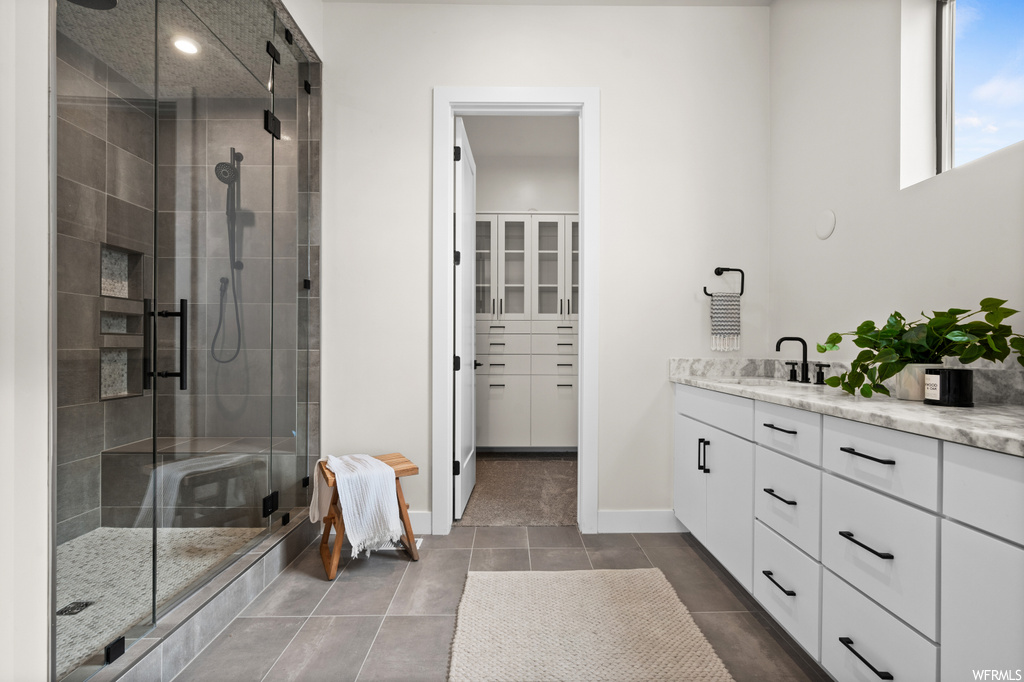 Bathroom with tile flooring, a shower with door, and vanity
