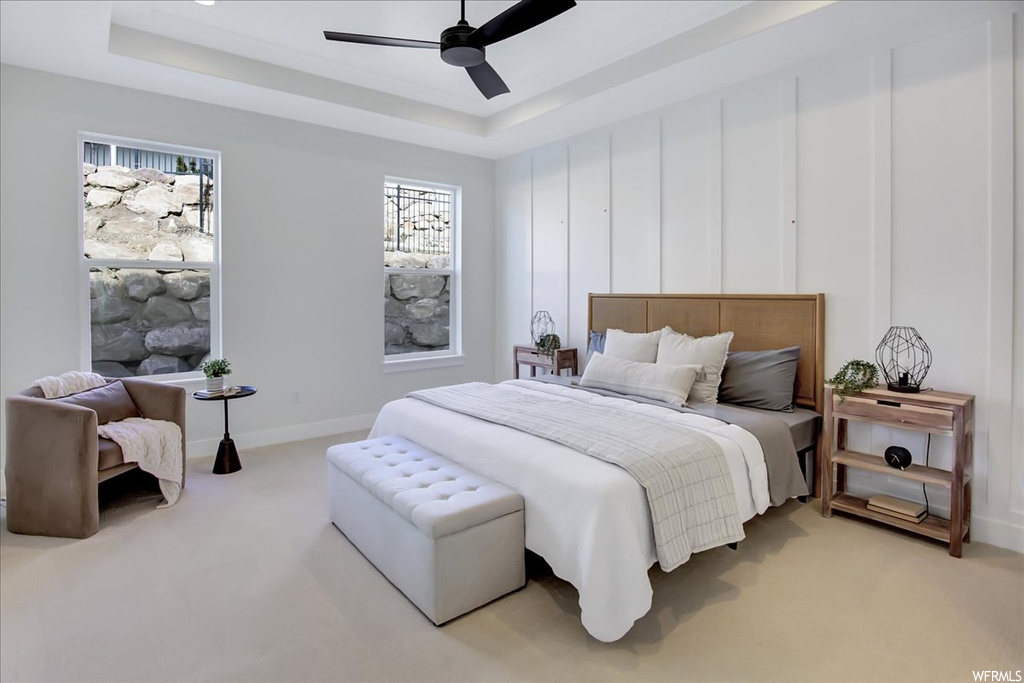 Carpeted bedroom with ceiling fan and a raised ceiling