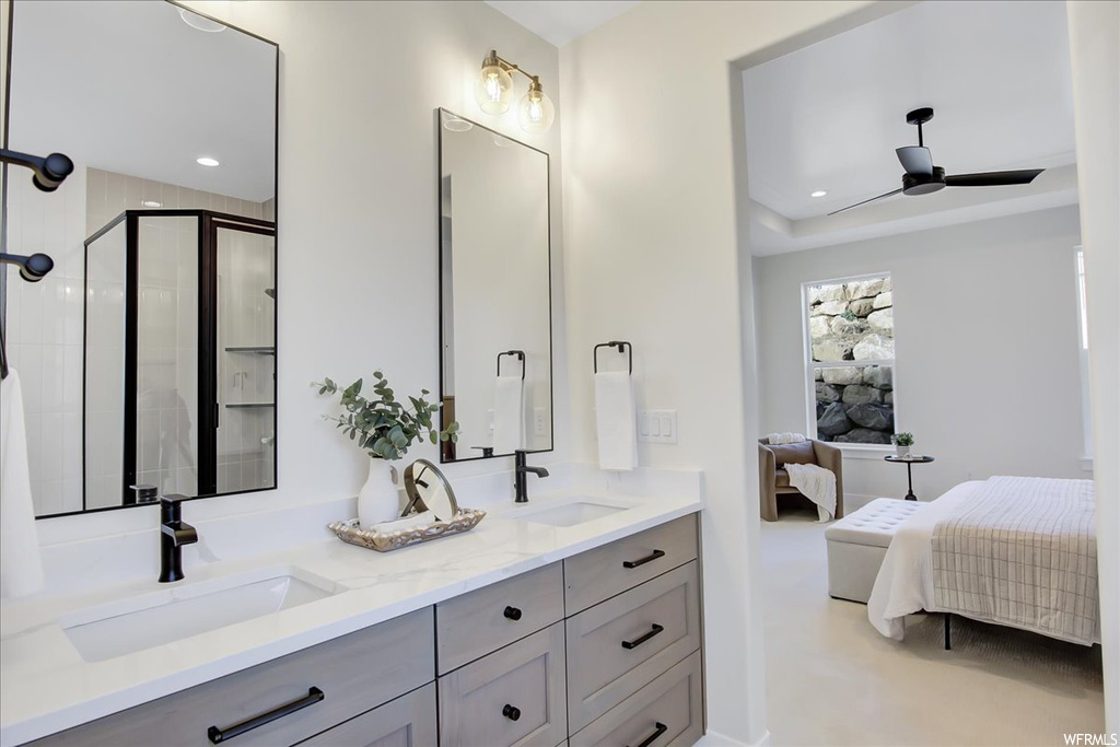 Bathroom featuring dual vanity, ceiling fan, and a shower with shower door