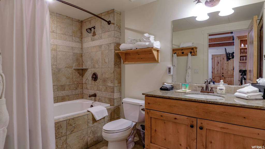 Full bathroom with toilet, large vanity, and shower / tub combo