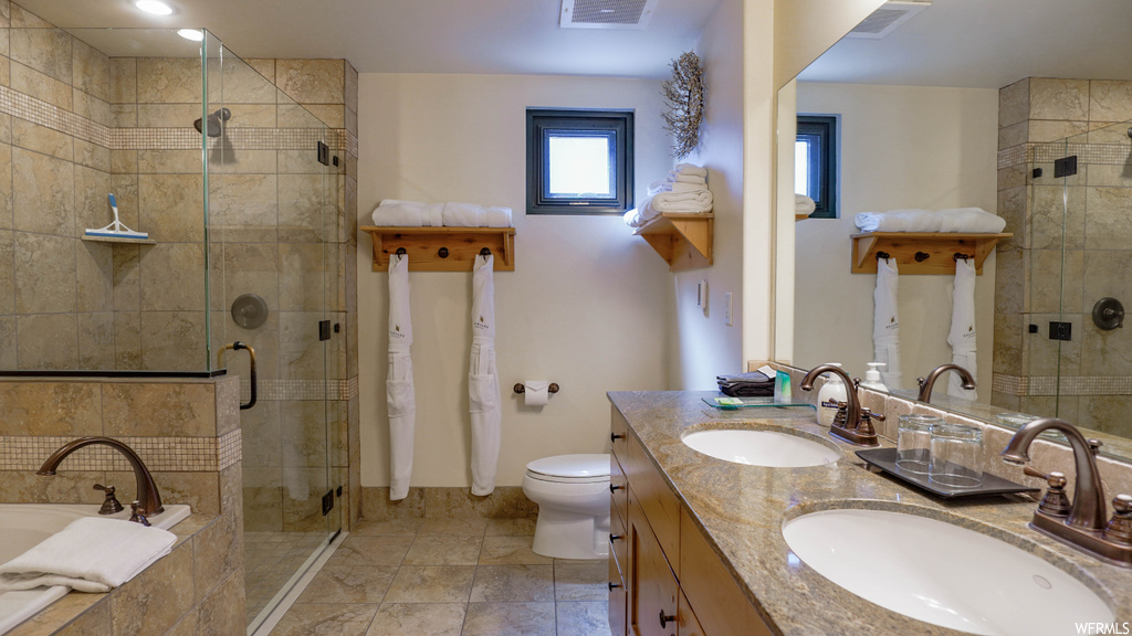 Full bathroom featuring toilet, tile floors, shower with separate bathtub, and dual bowl vanity