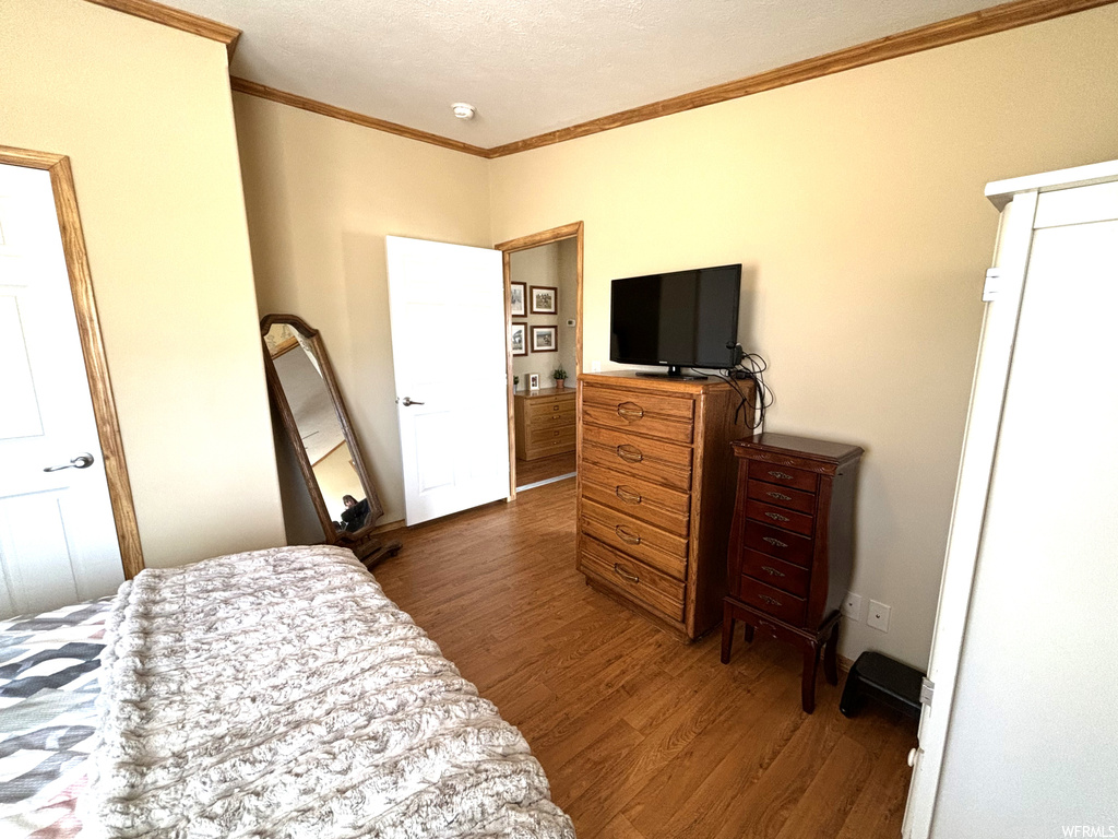 Bedroom with ornamental molding and dark hardwood / wood-style floors