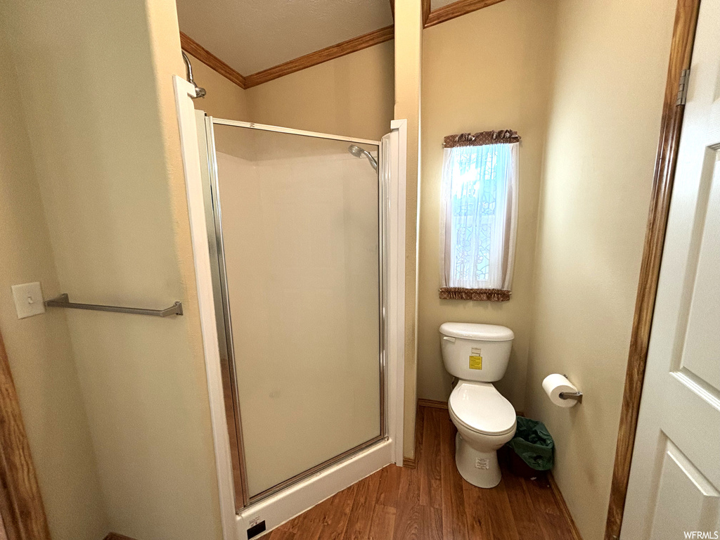 Bathroom featuring toilet, crown molding, a shower with shower door, and hardwood / wood-style flooring