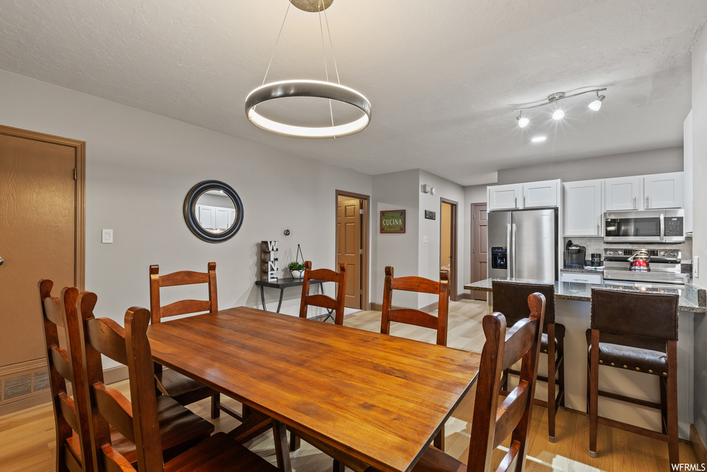Dining room with light hardwood / wood-style floors and rail lighting