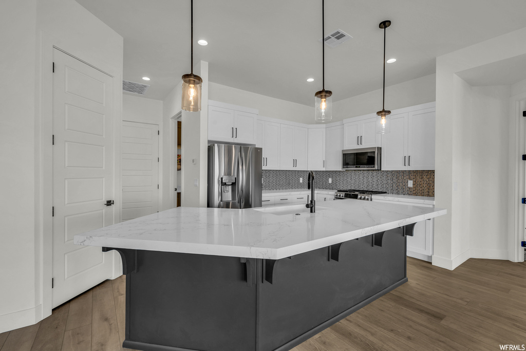 Kitchen with tasteful backsplash, dark wood-type flooring, pendant lighting, and stainless steel appliances