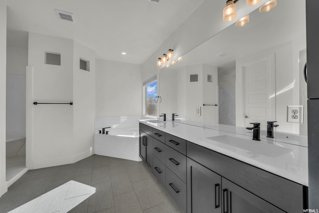 Bathroom with dual vanity, tile floors, and a bathing tub