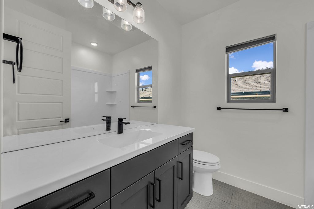 Bathroom featuring toilet, plenty of natural light, tile floors, and oversized vanity