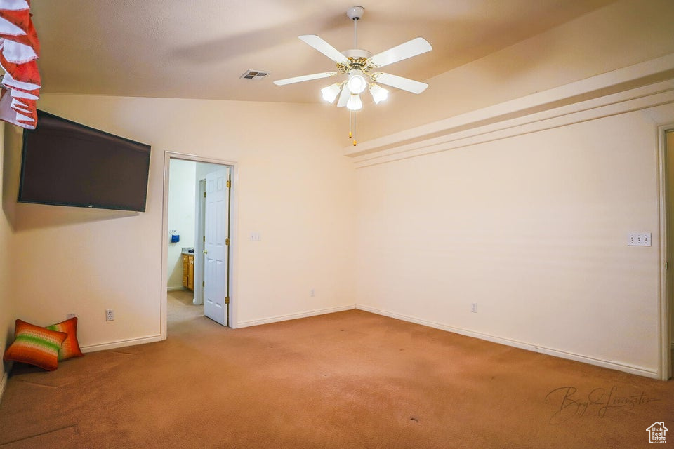 Empty room with lofted ceiling, ceiling fan, and carpet flooring