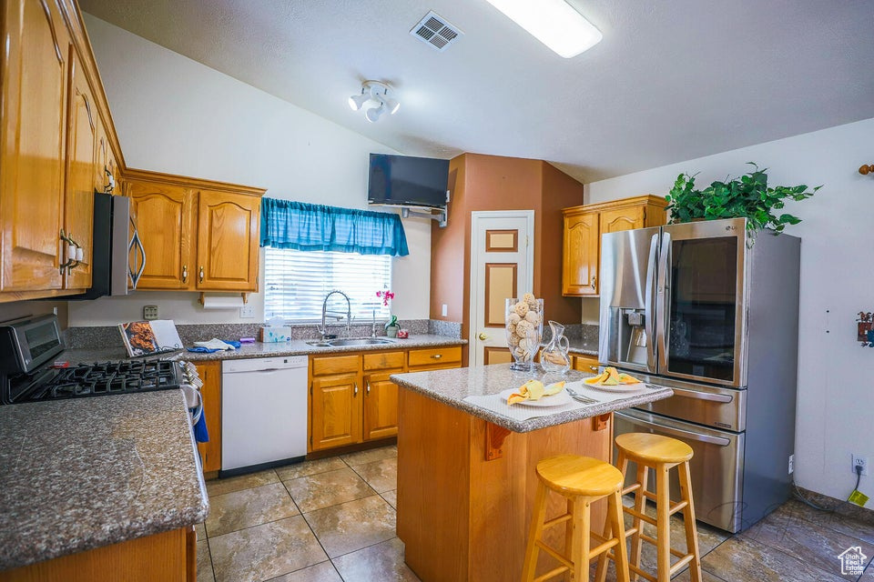 Kitchen featuring a center island, a kitchen breakfast bar, stainless steel appliances, tile flooring, and sink
