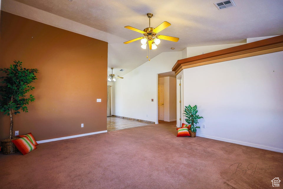 Unfurnished room with lofted ceiling, ceiling fan, and carpet flooring