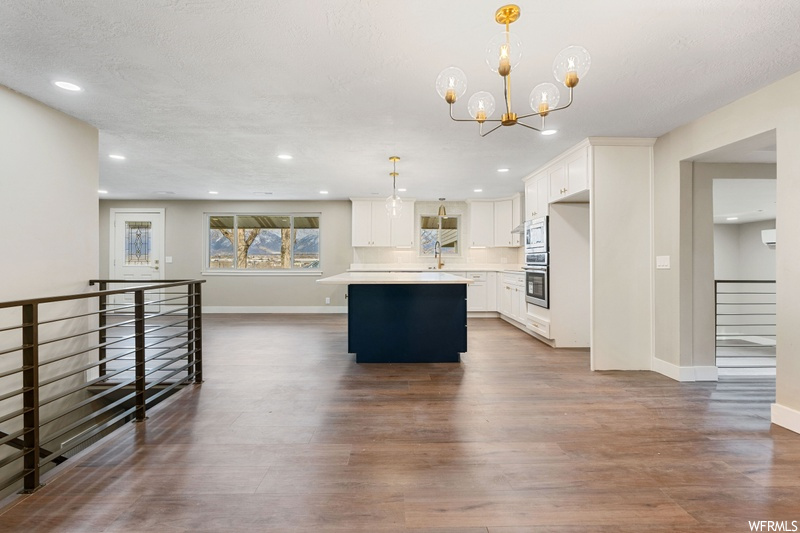 Kitchen featuring decorative light fixtures, dark hardwood / wood-style flooring, white cabinetry, and appliances with stainless steel finishes