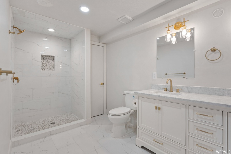 Bathroom with tiled shower, toilet, tile floors, and oversized vanity