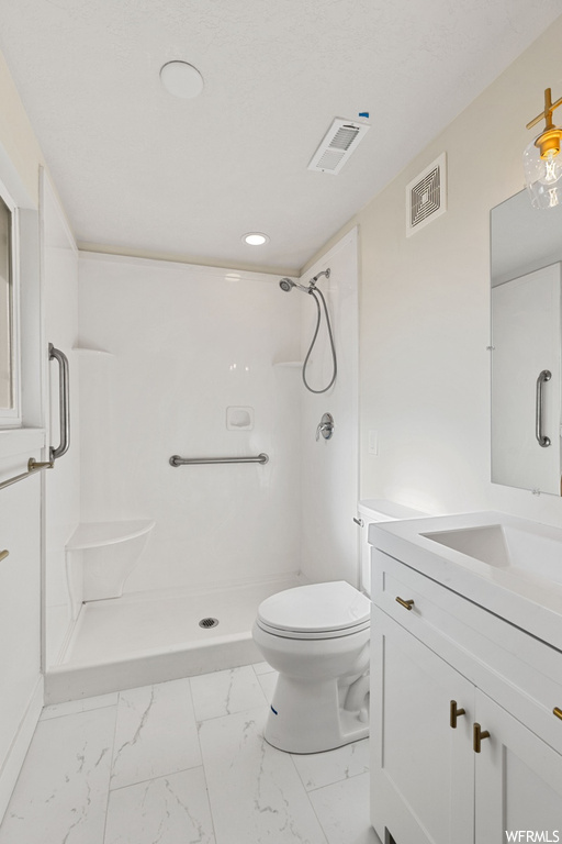 Bathroom featuring toilet, tile floors, a shower, and vanity with extensive cabinet space