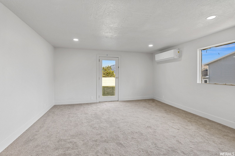Carpeted spare room with a textured ceiling and a wall unit AC