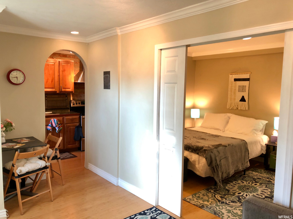 Bedroom featuring light hardwood / wood-style flooring, ornamental molding, and a closet