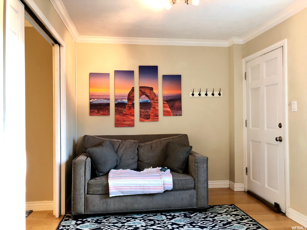 Living room featuring ornamental molding and light hardwood / wood-style flooring