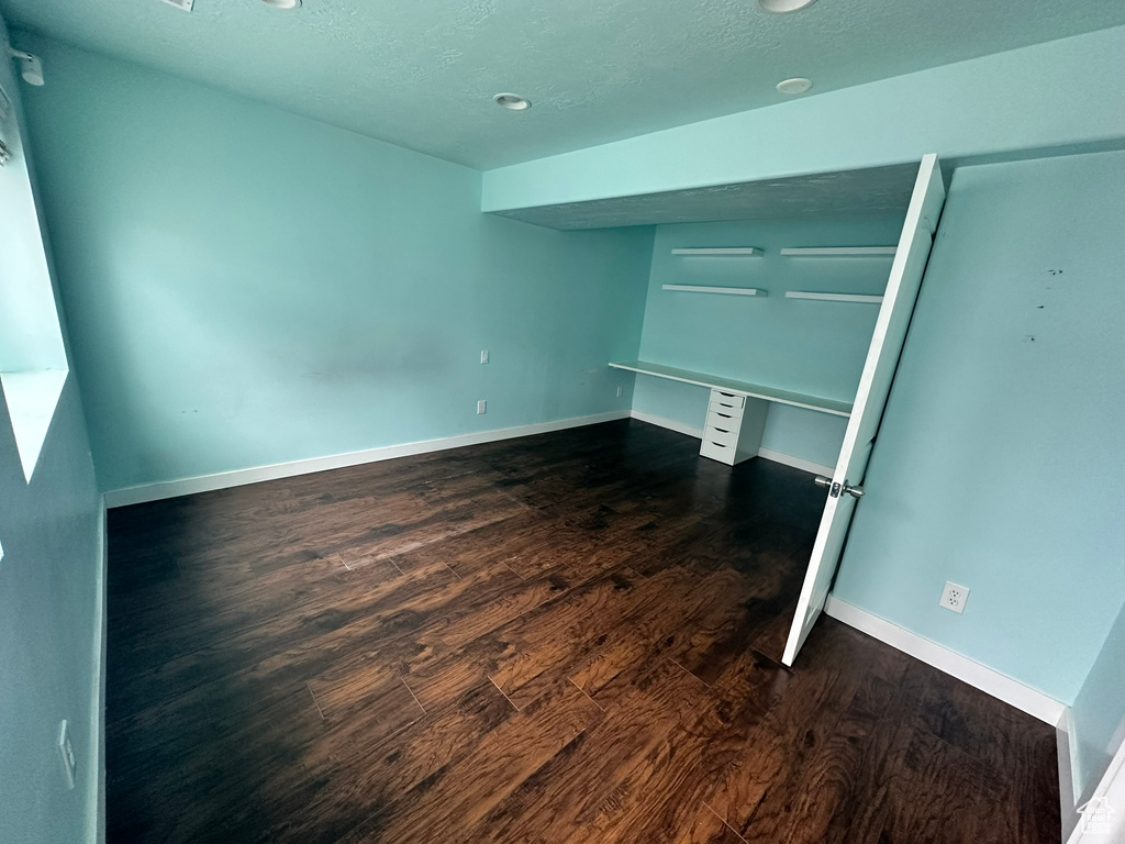 Unfurnished bedroom featuring a closet, a textured ceiling, and dark hardwood / wood-style floors