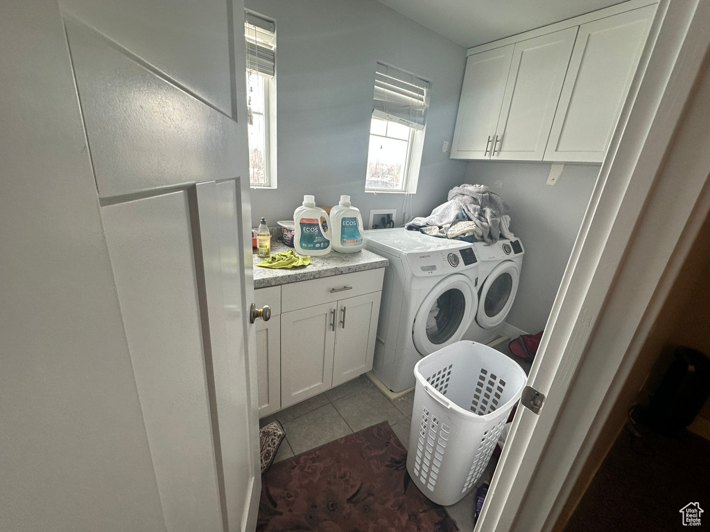 Clothes washing area featuring washer hookup, washer and clothes dryer, cabinets, and light tile floors