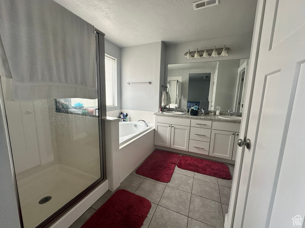 Bathroom with a textured ceiling, plus walk in shower, tile flooring, and dual bowl vanity