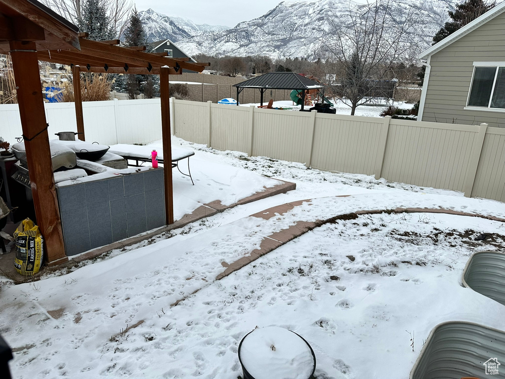 Yard covered in snow featuring a gazebo and a mountain view
