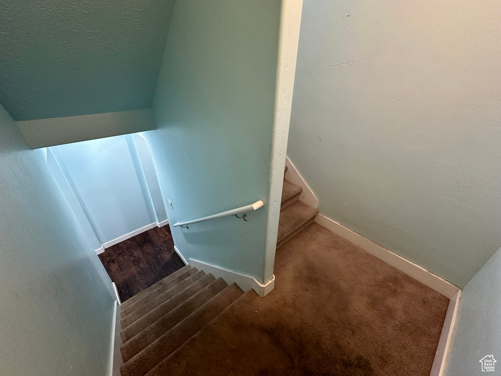 Stairs featuring vaulted ceiling and carpet