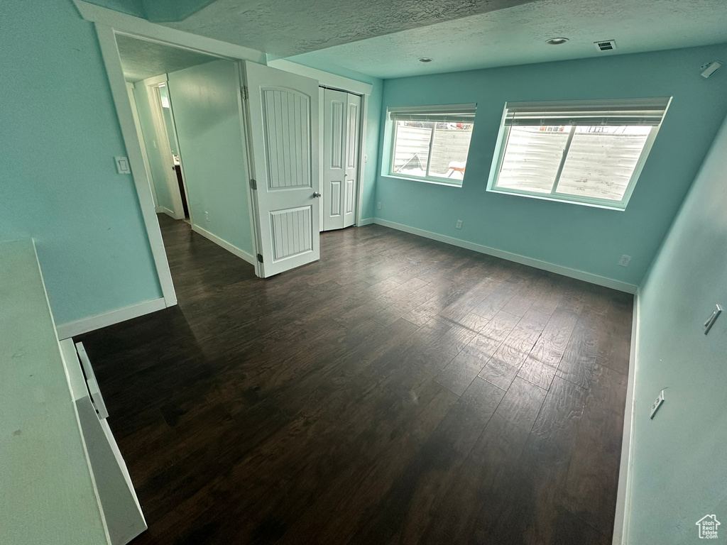 Empty room featuring a textured ceiling and dark hardwood / wood-style floors