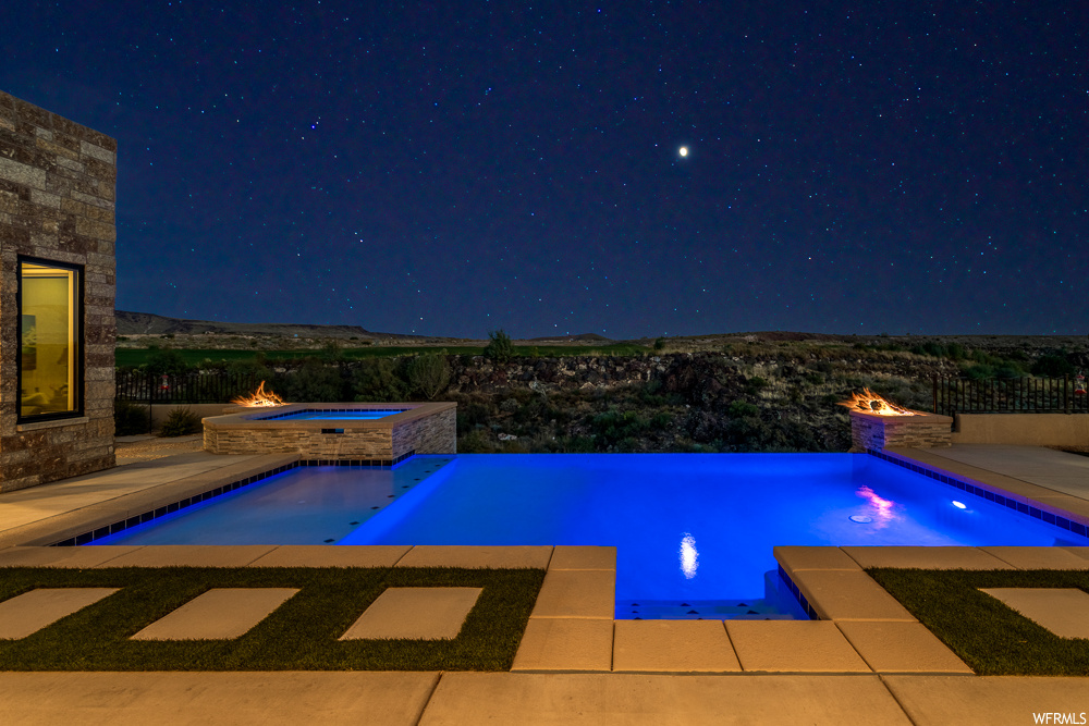Pool at twilight with a patio and an in ground hot tub