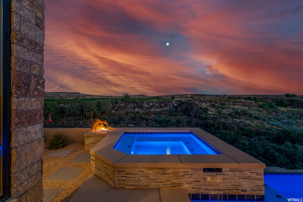 Pool at dusk with a patio area and an in ground hot tub