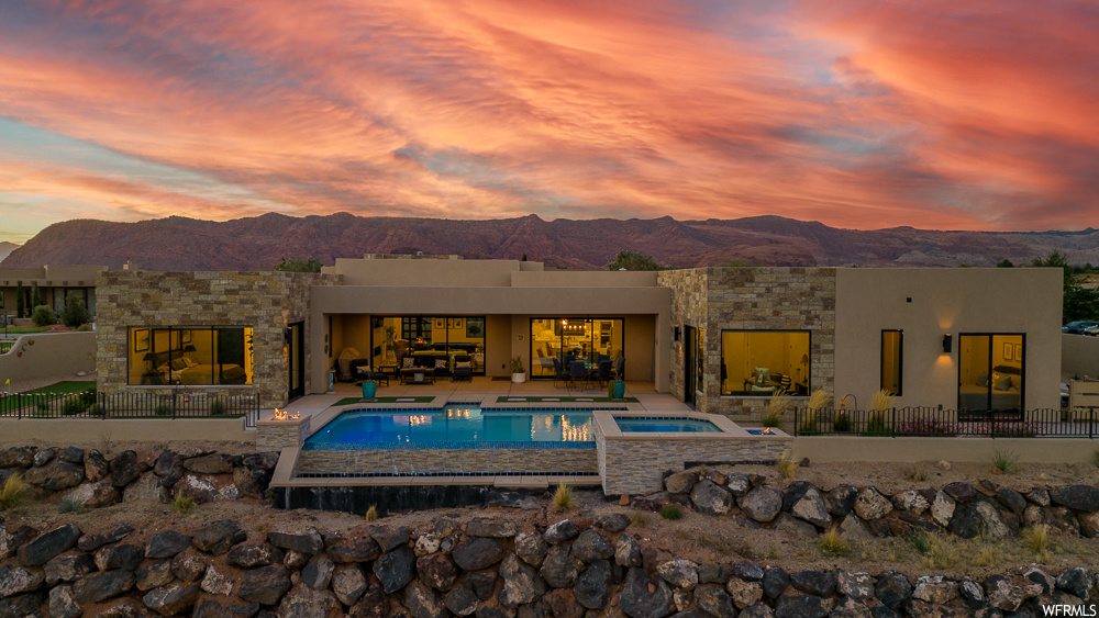Pool at dusk featuring an in ground hot tub, a patio area, and a mountain view