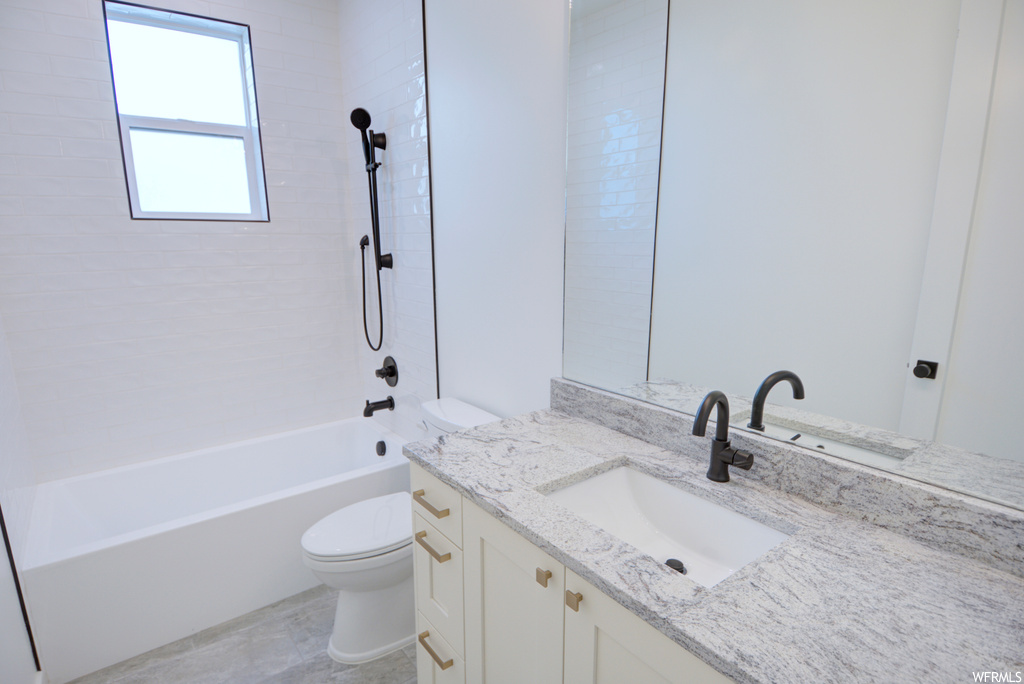Full bathroom featuring toilet, tiled shower / bath combo, tile floors, and vanity