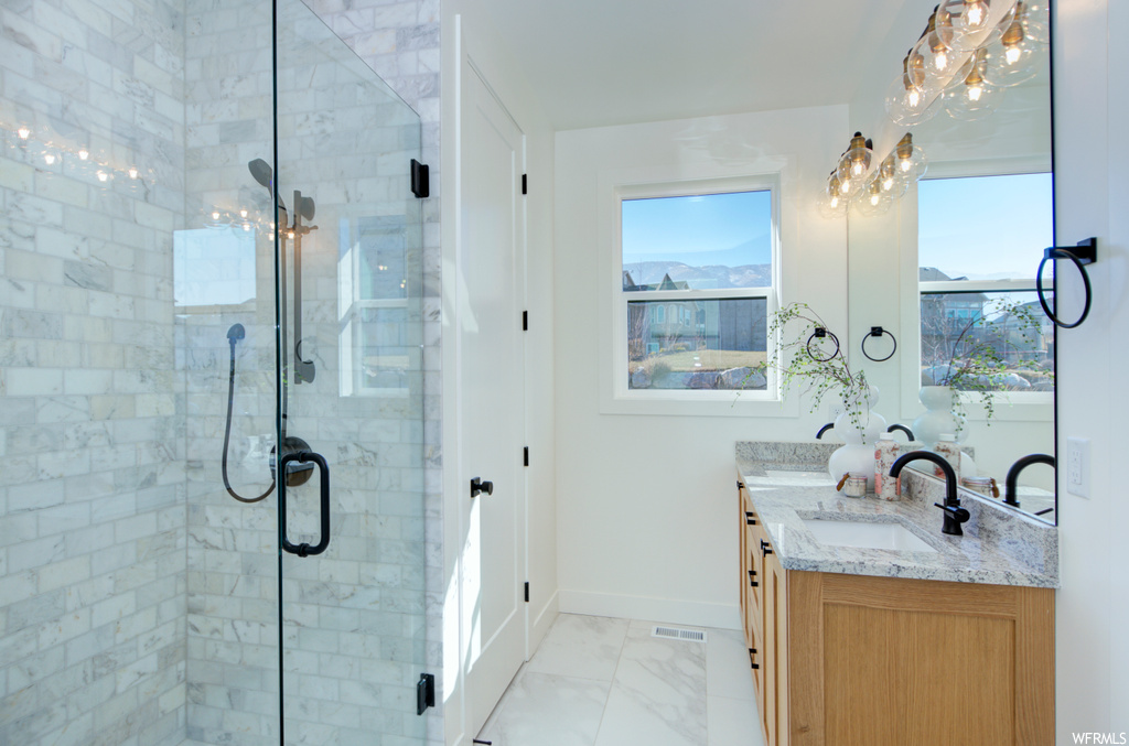 Bathroom with tile flooring, double sink vanity, a shower with shower door, and a chandelier