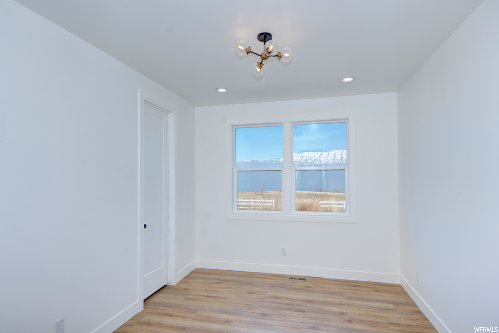 Spare room with a water view, light hardwood / wood-style flooring, and a chandelier