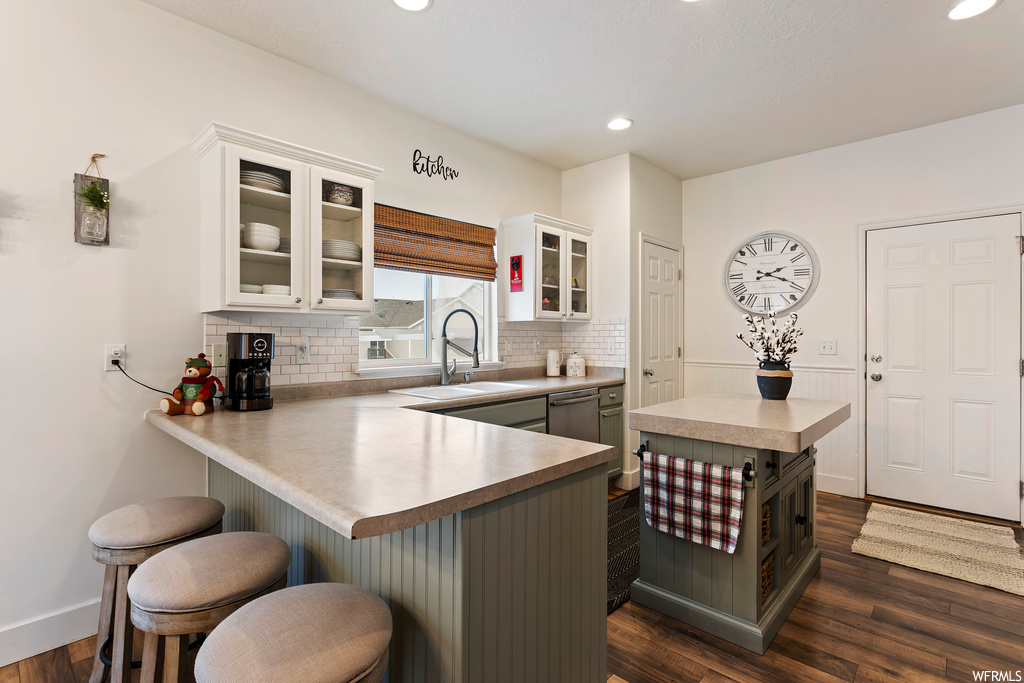 Kitchen with dark hardwood / wood-style floors, a kitchen breakfast bar, sink, and kitchen peninsula