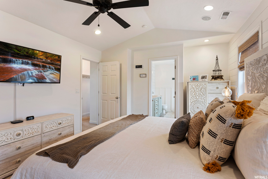 Carpeted bedroom featuring ensuite bath, ceiling fan, and vaulted ceiling