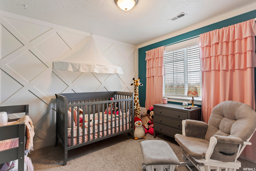 Carpeted bedroom with a textured ceiling and a nursery area