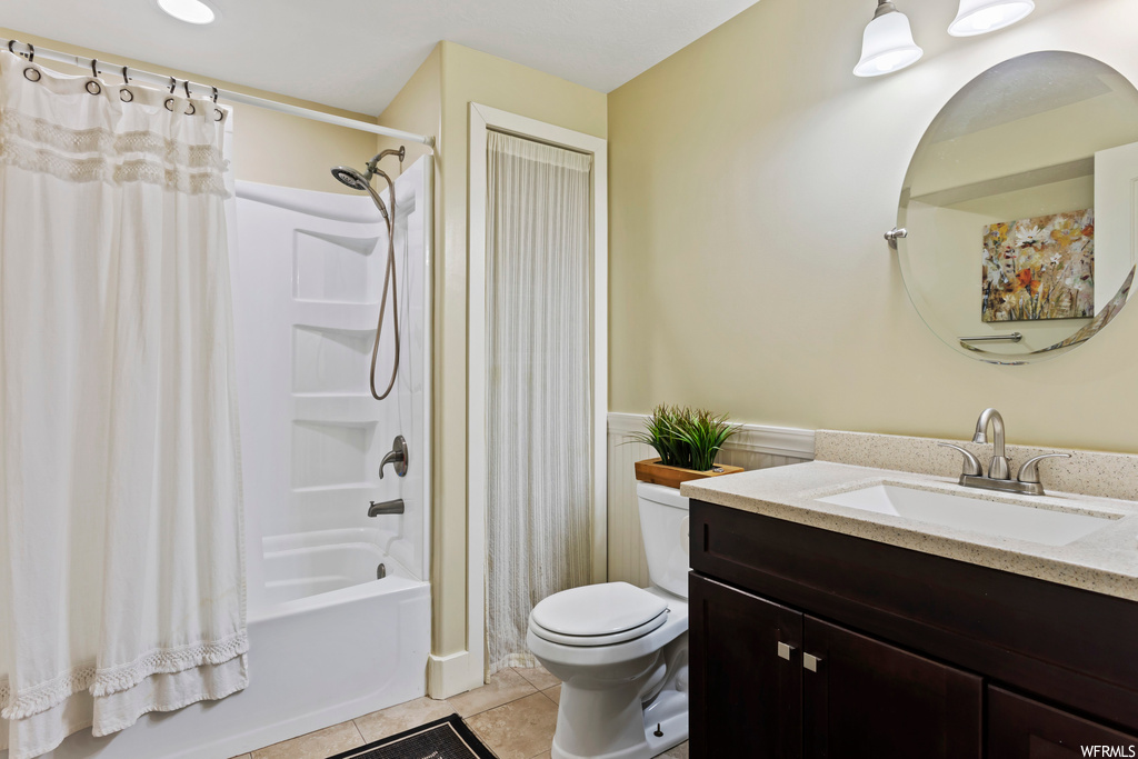 Full bathroom featuring toilet, shower / bath combo with shower curtain, tile floors, and large vanity