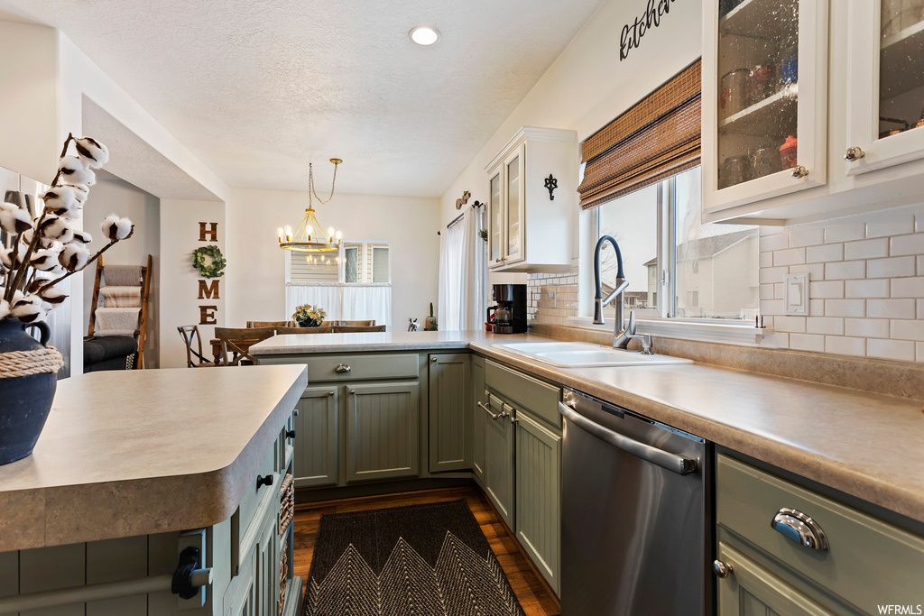 Kitchen with dishwasher, sink, pendant lighting, tasteful backsplash, and a notable chandelier