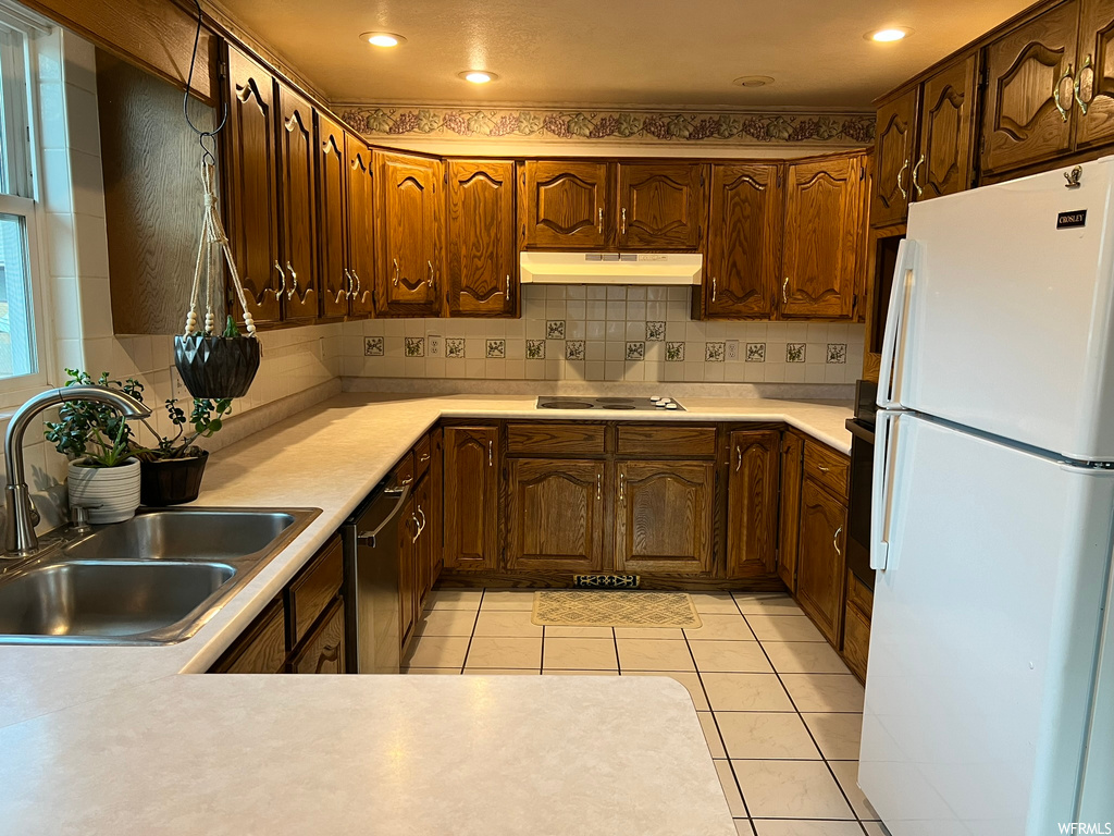 Kitchen featuring white appliances, light tile flooring, tasteful backsplash, and sink