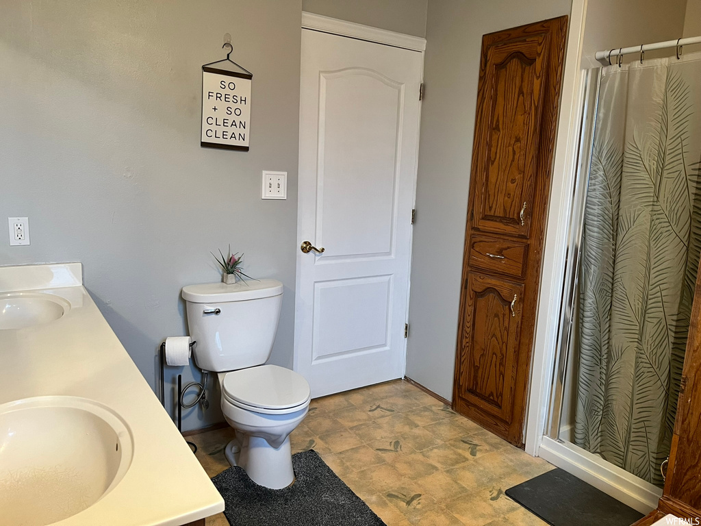 Bathroom with toilet, tile flooring, and dual vanity