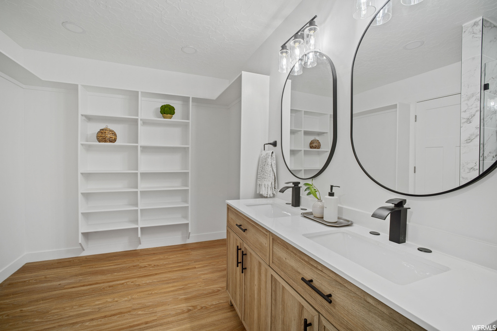 Bathroom featuring hardwood / wood-style flooring, a textured ceiling, and double vanity