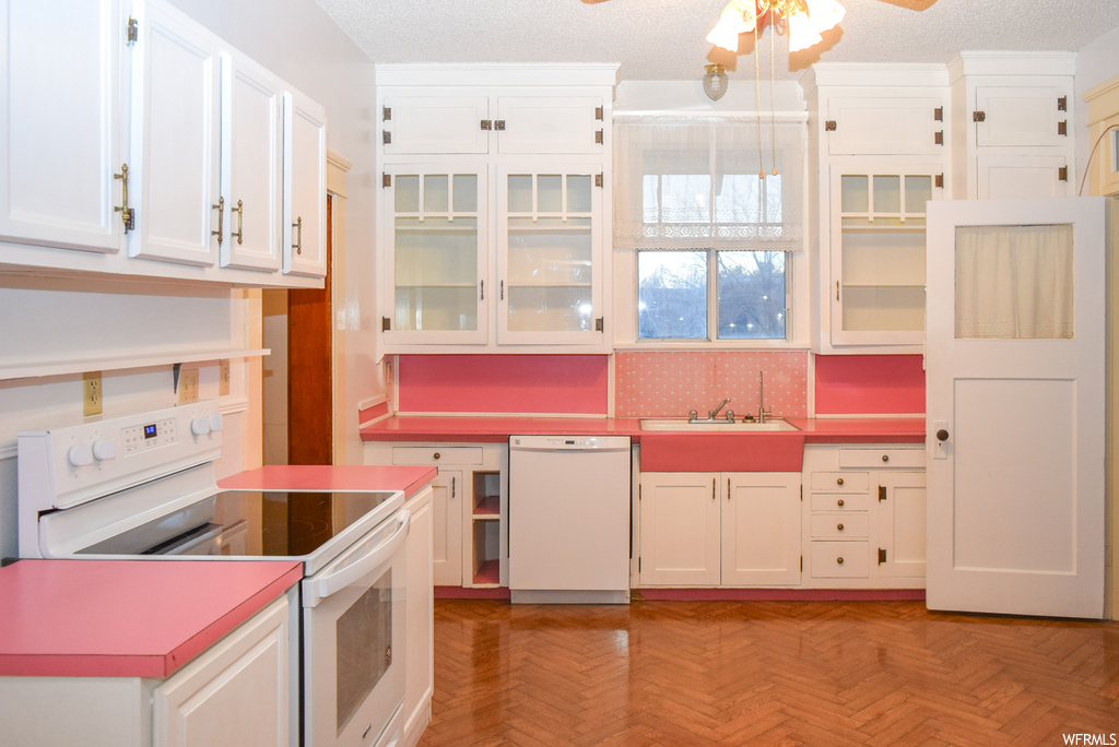 Kitchen with white cabinets, white appliances, ceiling fan, and light parquet flooring