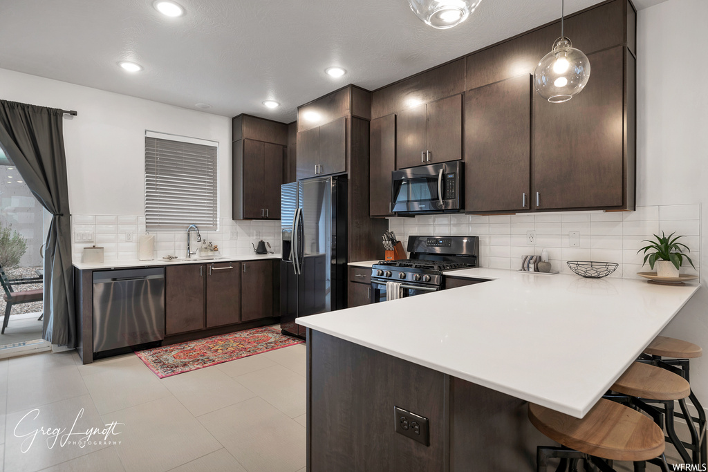 Kitchen featuring backsplash, dark brown cabinetry, and appliances with stainless steel finishes