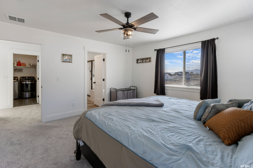 Bedroom featuring ceiling fan, connected bathroom, and light carpet
