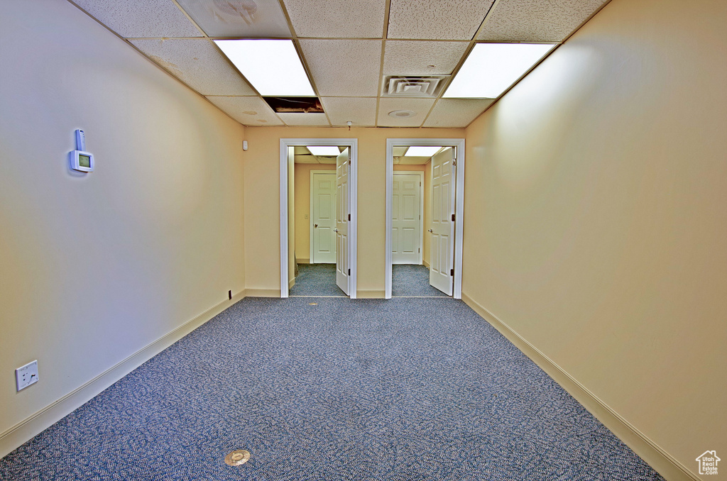 Empty room with a paneled ceiling and dark carpet