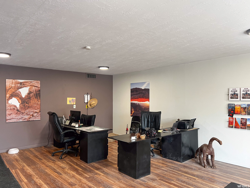 Office space with dark wood-type flooring and a textured ceiling