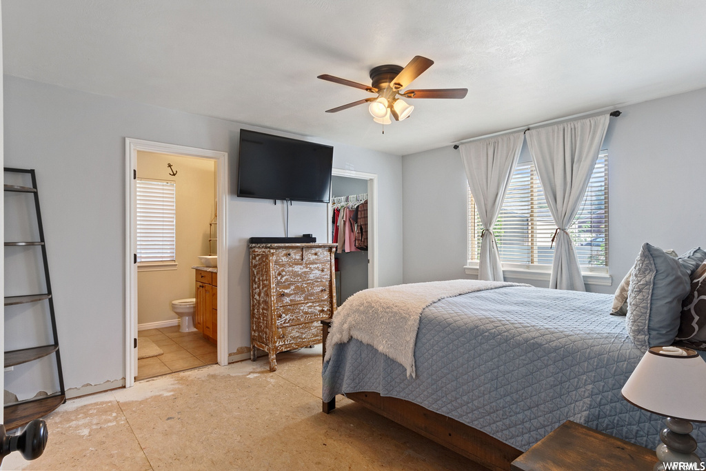 Bedroom featuring light tile flooring, a spacious closet, ceiling fan, a closet, and connected bathroom