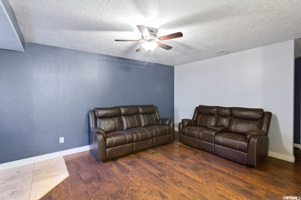 Living room with dark hardwood / wood-style floors, ceiling fan, and a textured ceiling