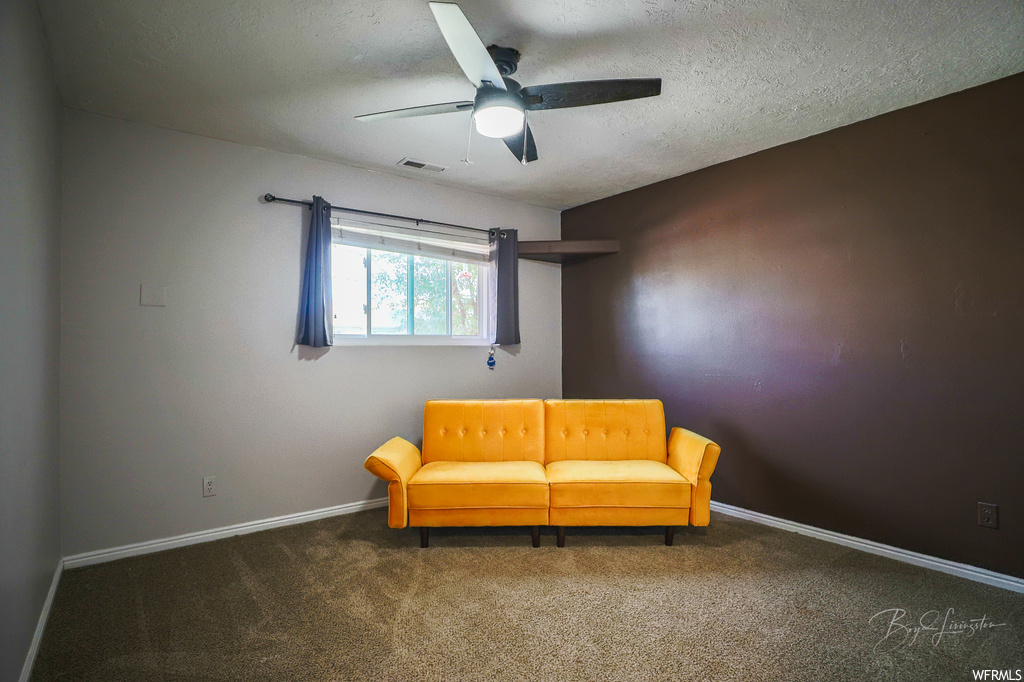 Sitting room with ceiling fan, a textured ceiling, and dark colored carpet