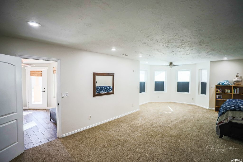 Unfurnished bedroom featuring a textured ceiling and light carpet