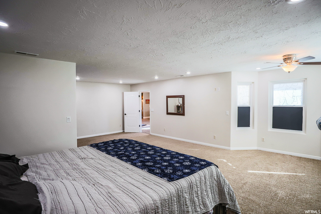 Bedroom featuring light carpet, ceiling fan, and a textured ceiling